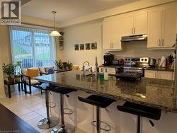 Kitchen island featuring a polished speckled countertop, integrated sink, and bar seating - 