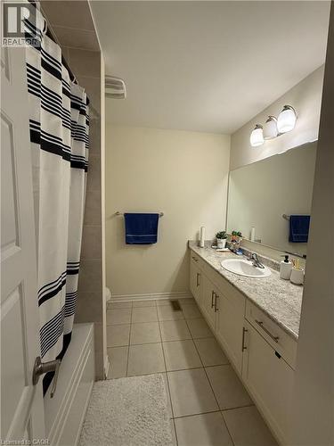Bathroom featuring a built-in bathtub with tiled surround, a large vanity with an integrated sink, and an expansive wall-mounted mirror - 63 Ridge Road, Cambridge, ON - Indoor Photo Showing Bathroom