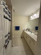 Bathroom featuring a built-in bathtub with tiled surround, a large vanity with an integrated sink, and an expansive wall-mounted mirror - 