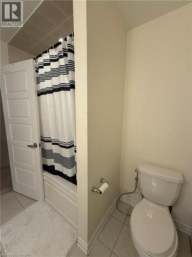 Bathroom featuring a white panel door, tiled flooring, a bathtub with a tiled surround, and a white toilet - 63 Ridge Road, Cambridge, ON - Indoor Photo Showing Bathroom