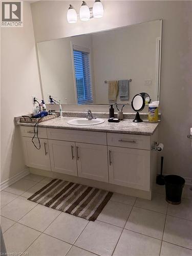 Vanity area featuring a wide mirror, white cabinetry, integrated sink, and light-toned countertop - 63 Ridge Road, Cambridge, ON - Indoor Photo Showing Bathroom