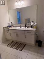 Vanity area featuring a wide mirror, white cabinetry, integrated sink, and light-toned countertop - 