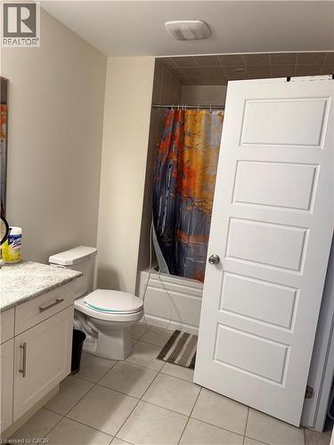 Bathroom featuring a light-toned vanity with granite countertop, white paneled cabinetry, and a white toilet - 63 Ridge Road, Cambridge, ON - Indoor Photo Showing Bathroom