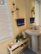 Bathroom featuring a pedestal sink, wall-mounted mirror, and white window blinds - 