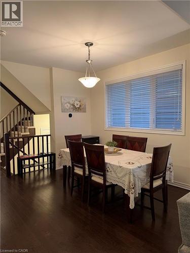 Dining area featuring wood-finish flooring, a large window with blinds, and a suspended ceiling light fixture - 63 Ridge Road, Cambridge, ON - Indoor Photo Showing Dining Room