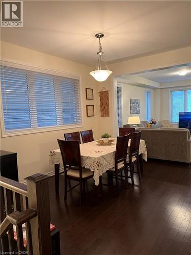 Open-concept dining area featuring dark wood-finish flooring, a contemporary pendant light fixture, and large windows with horizontal blinds - 63 Ridge Road, Cambridge, ON - Indoor Photo Showing Dining Room