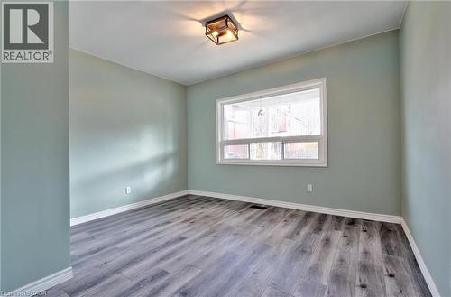 Room featuring wood-finish flooring, light-toned walls, a white-framed window, and a flush-mount ceiling light fixture - 111 Gibson Avenue Unit# A, Hamilton, ON - Indoor Photo Showing Other Room