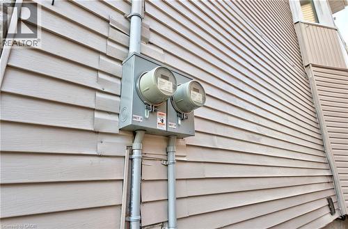 Exterior wall featuring horizontal siding, a dual-meter electrical service panel, and conduit piping - 111 Gibson Avenue Unit# A, Hamilton, ON - Outdoor