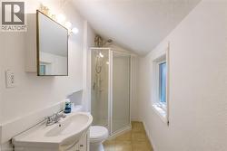 Bathroom featuring a corner shower enclosure, single vanity with integrated sink, wall-mounted medicine cabinet, and a window - 