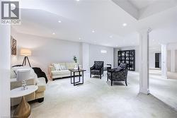 Expansive finished lower level featuring recessed lighting, light-toned carpeting, structural columns with decorative trim, and an integrated built-in shelving unit - 