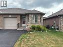 Stone and brick-clad exterior featuring a single-car garage with a light-colored door, a paved driveway, and a front entry with a small porch and bay window - 49 Millcroft Drive, Simcoe, ON  - Outdoor 