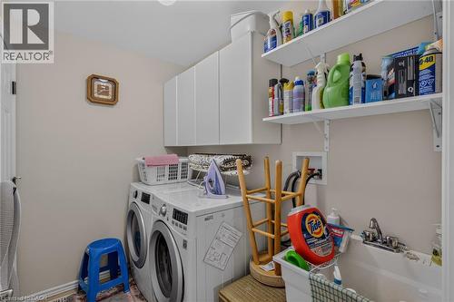 tile floor laundry sink appliances included plenty of cupboards and shelving off the garage entrance - 49 Millcroft Drive, Simcoe, ON - Indoor Photo Showing Laundry Room