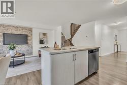Kitchen island with a double basin sink, integrated dishwasher, and light cabinetry - 
