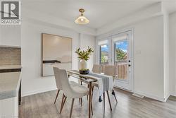 Dining area featuring wood-finish flooring, a contemporary glass-top table, and a pair of white French doors - 