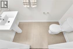 Pedestal sink and toilet in a light-toned bathroom featuring tile flooring, white walls, and bright white trim - 