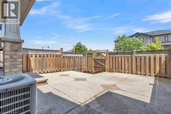 Expansive concrete patio area featuring integrated paver accents, surrounded by a wood privacy fence with lattice detailing and a functional gate - 