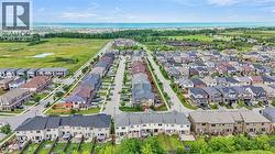 Expansive community featuring numerous residential properties with diverse architectural styles, a visible body of water in the background, and surrounding green spaces - 
