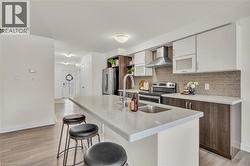 Modern kitchen featuring a large island with an undermount sink, light-toned countertops, and two-tone cabinetry - 