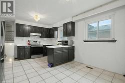 Kitchen featuring dark cabinetry, white countertops, a stainless steel range, and a white tile backsplash - 