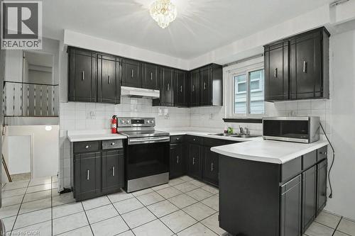 Kitchen featuring dark cabinetry, white square tile flooring, white subway tile backsplash, and a stainless steel electric range - 396 Pinemeadow Avenue, Mississauga, ON - Indoor Photo Showing Kitchen
