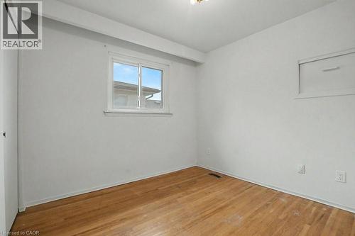 Bright room featuring a window with a white frame, wood-finish flooring, white baseboards, and a white ceiling with a flush-mount light fixture - 396 Pinemeadow Avenue, Mississauga, ON - Indoor Photo Showing Other Room