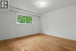 Light-filled interior space featuring wood-finish flooring, white walls, and a white framed window - 