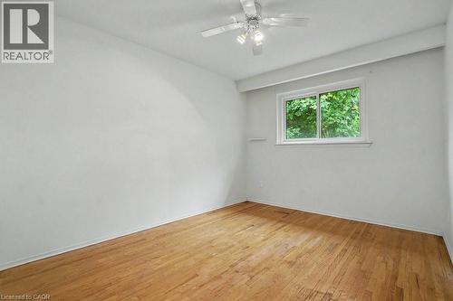 Room featuring hardwood flooring, white walls, a white ceiling fan with integrated lighting, and a window with white trim - 396 Pinemeadow Avenue, Mississauga, ON - Indoor Photo Showing Other Room