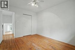 Hardwood-style flooring throughout, white walls, and a ceiling fan with integrated lighting - 