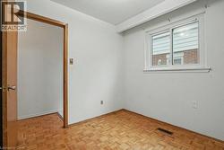 Bright room featuring a parquet wood-finish floor, a large window with white trim, and a white interior door frame - 