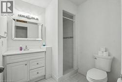 Bathroom featuring a single vanity with storage, a rectangular mirror, and a walk-in shower with decorative tile accent - 