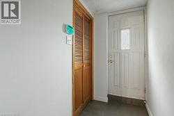 Entryway featuring a paneled door with decorative glass, brass hardware, and durable tile flooring - 