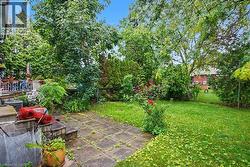 Private backyard featuring mature trees, established plantings, a paved patio, and a grass lawn - 