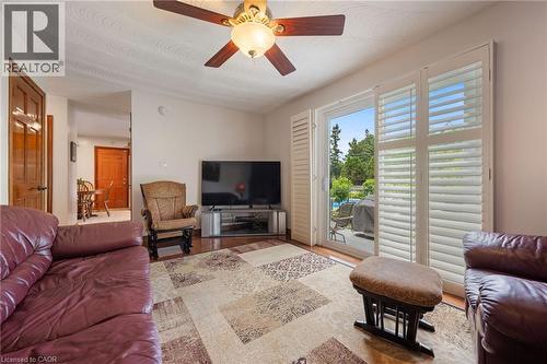 Living area featuring wood-finish flooring, a ceiling fan, and white plantation shutters on the sliding glass door - 7 Thomson Road, Simcoe, ON - Indoor Photo Showing Living Room