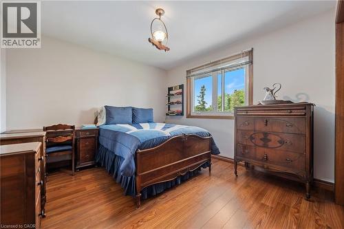 Bright bedroom featuring wood-finish flooring, a large window with natural light, a ceiling-mounted light fixture, and light-toned walls - 7 Thomson Road, Simcoe, ON - Indoor Photo Showing Bedroom