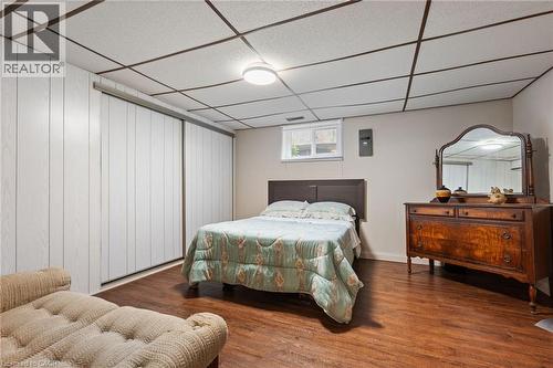 Wall-to-wall sliding panel doors define this room, featuring wood-finish flooring and a drop ceiling with integrated lighting - 7 Thomson Road, Simcoe, ON - Indoor Photo Showing Bedroom