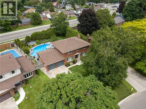 Brick exterior residence with a two-car garage, mature trees, and an in-ground swimming pool - 7 Thomson Road, Simcoe, ON - Outdoor With In Ground Pool