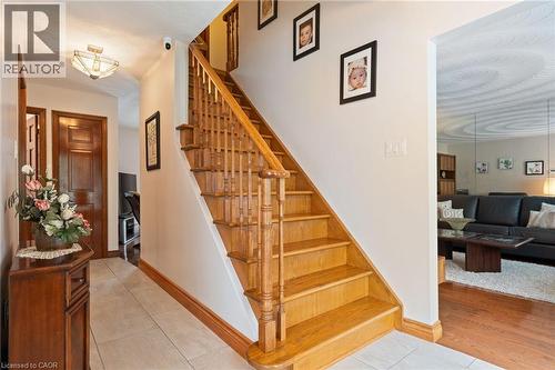 Solid wood staircase with baluster railing, showcasing a paneled wood door and light tile flooring - 7 Thomson Road, Simcoe, ON - Indoor Photo Showing Other Room