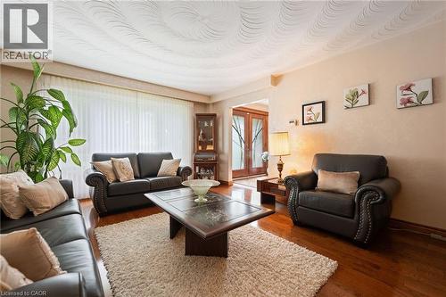 Spacious living area featuring wood-finish flooring, a textured ceiling, and a broad window with vertical blinds - 7 Thomson Road, Simcoe, ON - Indoor Photo Showing Living Room