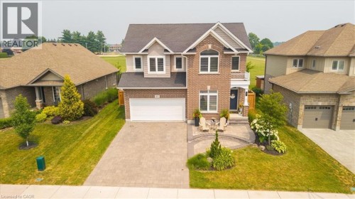 Brick and siding exterior featuring a two-car garage, arched window, and a paver stone driveway - 87 Boyd Boulevard, Thamesford, ON - Outdoor With Facade