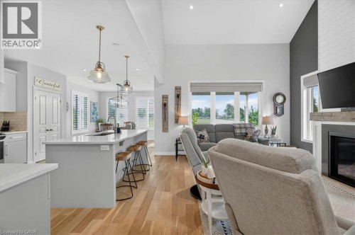 Open-concept living area featuring high vaulted ceilings, light wood-finish flooring, a contemporary fireplace with a shiplap accent wall, and a kitchen island with pendant lighting - 87 Boyd Boulevard, Thamesford, ON - Indoor With Fireplace