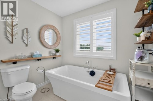 Freestanding soaking tub with a wall-mounted faucet, complemented by white plantation shutters - 87 Boyd Boulevard, Thamesford, ON - Indoor Photo Showing Bathroom