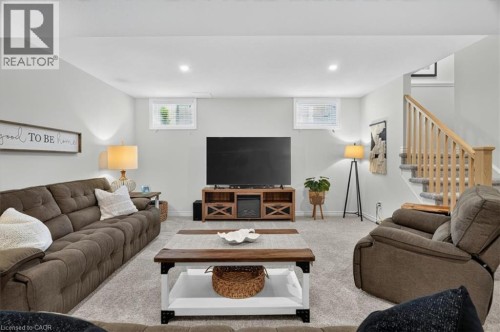Spacious lower level living area featuring light gray walls, plush gray carpeting, and two egress windows providing natural light - 87 Boyd Boulevard, Thamesford, ON - Indoor Photo Showing Living Room