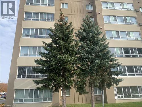 Mid-rise building exterior with a neutral-toned facade and multiple large windows - 65 Highland Crescent Unit# 201, Kitchener, ON - Outdoor With Facade