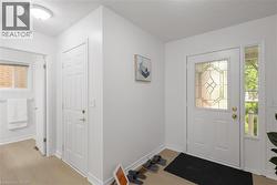 Entryway featuring light wood-finish flooring, white walls, and a decorative frosted glass front door - 