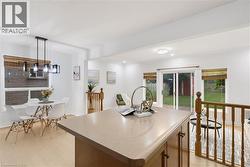 Open-concept interior featuring light wood-finish flooring, a kitchen island with counter space, and a dining area with a modern chandelier - 