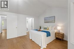 Spacious room featuring wood-finish flooring, a vaulted ceiling, and white painted walls - 