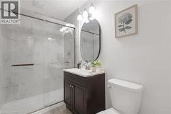 Bathroom featuring a dark wood vanity with a white countertop, oval mirror, and three-bulb vanity light - 
