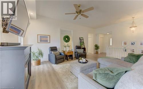 Vaulted ceiling living area featuring a ceiling fan, light wood-finish flooring, a decorative fireplace, and a white railing overlooking a lower space - 249 Dearborn Boulevard, Waterloo, ON - Indoor Photo Showing Living Room