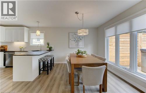 Kitchen and dining area featuring wood-finish flooring, white cabinetry, dark countertops, stainless steel appliances, and a large window - 249 Dearborn Boulevard, Waterloo, ON - Indoor Photo Showing Dining Room