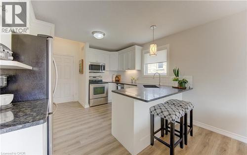 Well-appointed kitchen featuring light-toned cabinetry, stainless steel appliances, dark stone countertops, wood-finish flooring, and recessed lighting - 249 Dearborn Boulevard, Waterloo, ON - Indoor Photo Showing Kitchen